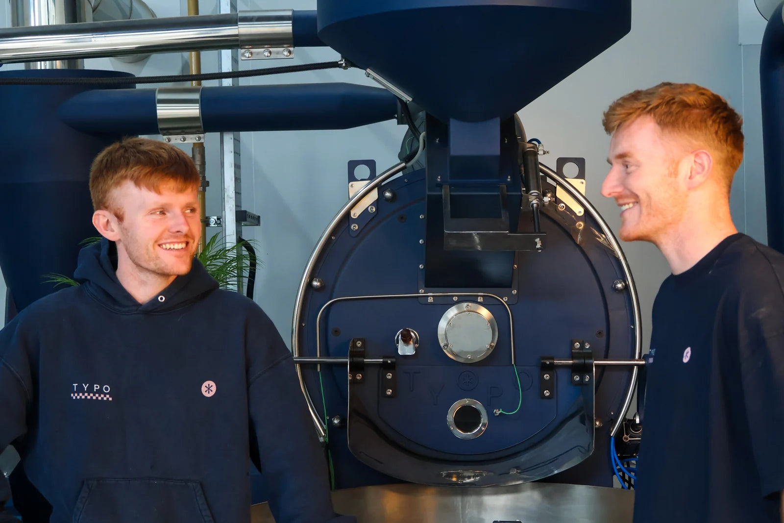Two of the Typo Coffee team beside their coffee roaster in Mullingar